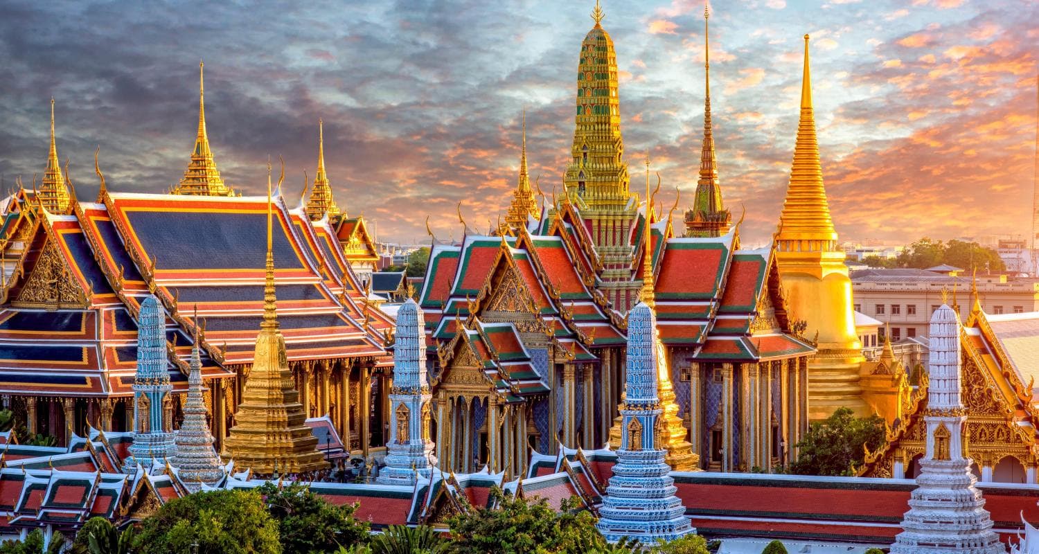Grand Palace and Wat Phra Kaew in Bangkok at sunset with golden stupas